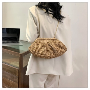Back view of model carrying khaki woven cloud bag with a gold metal chain strap