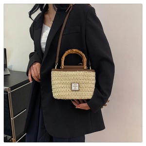Detail of woven straw tote bag with bamboo handle and 'Good Weekend' leather patch