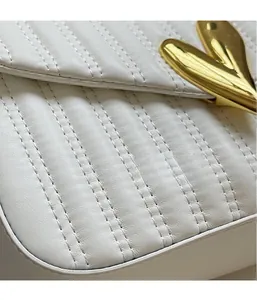 Detail shot of white quilted PU leather handbag featuring elegant gold V-shaped metal buckle