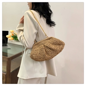 Detail of woven straw shoulder bag with elegant gold chain strap and chic cloud design