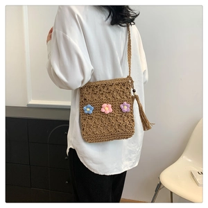 Detail of straw shoulder bag with colorful crochet flowers and trendy tassel accents