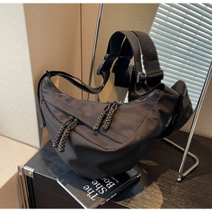 Minimalist black nylon half-moon crossbody bag with woven zipper and adjustable strap