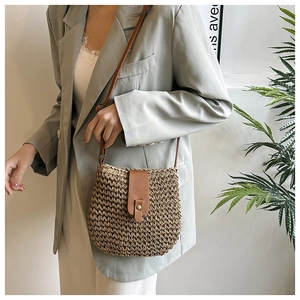 Detail of hand-woven raffia crossbody bag with brown leather strap and metal clasp