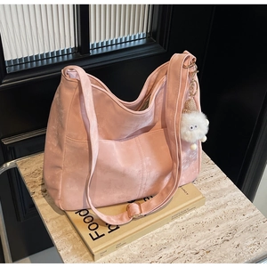 Pink faux suede crossbody bag with wide strap and plush pendant for spring 2024 fashion