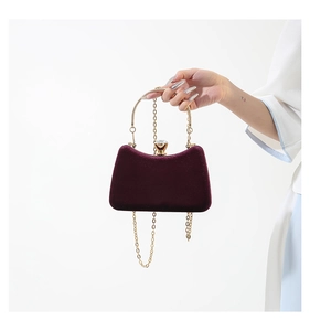 Detail of burgundy velvet evening bag featuring crystal clasp and gold metal chain strap