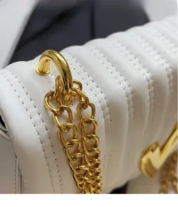 Detail of white quilted PU leather shoulder bag with polished gold chain and hardware
