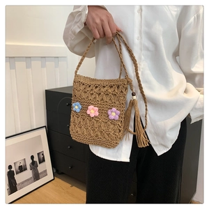 Detail of hand-woven straw crossbody bag with colorful crochet flowers and long side tassels