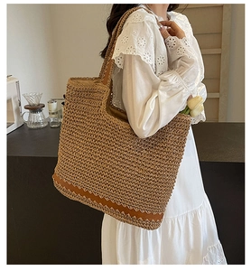 Close-up of woven straw tote bag featuring brown leather patchwork and modern resort style