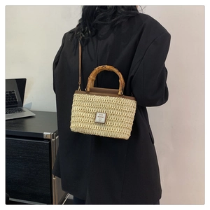 Detail of woven straw bag with natural bamboo handle and Good Weekend smiley patch