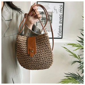 Detail shot of woven straw texture and brown leather flap with metal snap closure