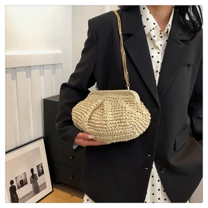 Detail of beige woven straw handbag with gold chain strap and textured fabric