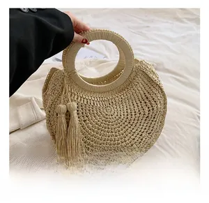 Detail showing beige woven straw handbag with unique round handle and chic side tassels