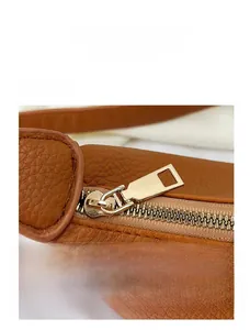 Close-up of golden metal zipper and brown litchi pattern leather on shoulder bag