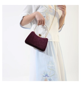 Detail of burgundy velvet evening clutch bag with golden ring handle and diamond clasp