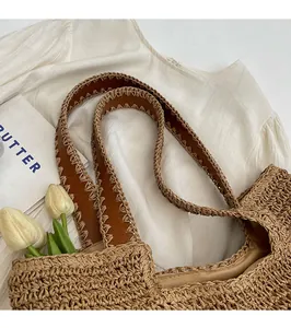 Detail of woven straw tote bag with brown shoulder straps and elegant interior lining
