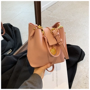 Sac seau en cuir grainé rose avec pendentif pièce dorée et finitions métalliques