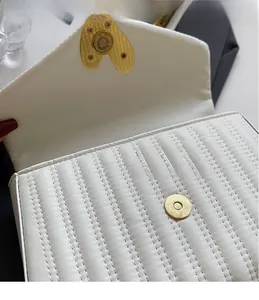 Close-up of white quilted PU leather bag featuring heart-shaped gold magnetic clasp
