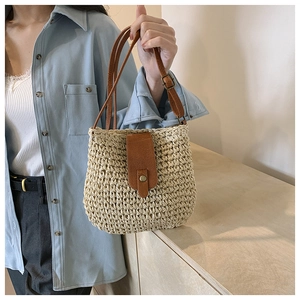 Detail shot of the woven texture and brown leather strap on the spring straw shoulder bag