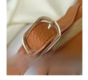 Detail of brown faux leather texture with adjustable gold metal buckle on shoulder strap