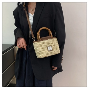 Fashionable woven straw bag featuring natural bamboo handle and brown leather straps