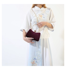 Detail of burgundy velvet evening bag with gold ring handle and gemstone clasp