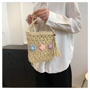 Detail of straw woven crossbody bag featuring colorful crochet flowers and tassel charms