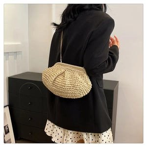 Detail of beige woven cloud bag with gold chain strap on a model in chic black blazer