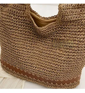 Detail of woven straw tote bag featuring brown leather wavy trim and spacious interior
