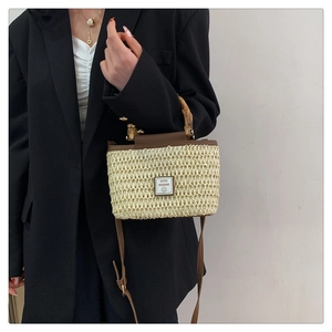 Detail of woven straw handbag with bamboo handle and Good Weekend patch on a model