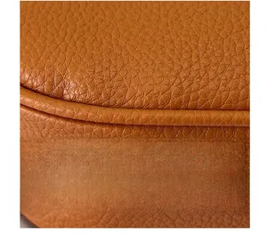 Macro shot of pebble grain faux leather surface with neat stitching on brown handbag edge