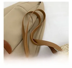Detailed close-up of woven shoulder bag featuring brown leather strap and white cross-stitching