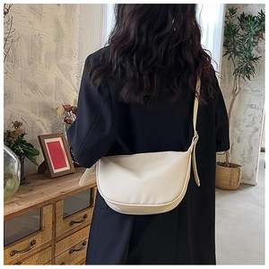 Close-up of cream crescent crossbody bag featuring premium lychee grain faux leather texture