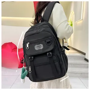 Détail du sac à dos noir en nylon avec plusieurs compartiments et pendentif vert