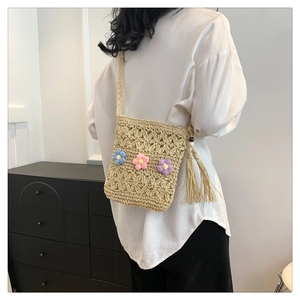 Close-up of handmade straw crossbody bag with floral crochet pattern and colorful flowers