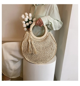 Detail of round straw handbag with long tassels and circular handles for summer