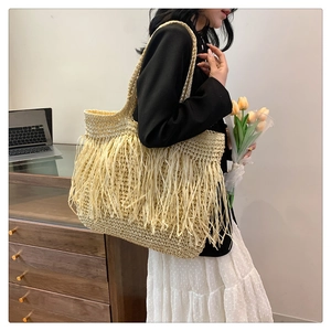 Dettaglio della borsa tote in paglia con lunghe frange e trama intrecciata stile boho
