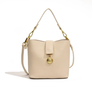 Sac seau minimaliste en cuir grainé beige avec garniture dorée et bandoulière amovible