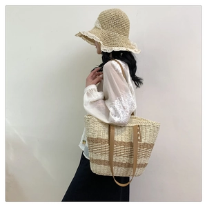 Detail of hand-woven straw tote bag with brown leather straps and striped texture