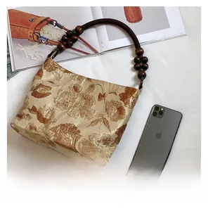 Details des floralen Jacquard-Seidenstoffs und des dekorativen Holzperlen-Griffs am Shopper