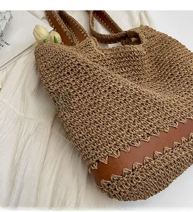 Detail of woven straw tote bag with brown leather stitching and zigzag edges