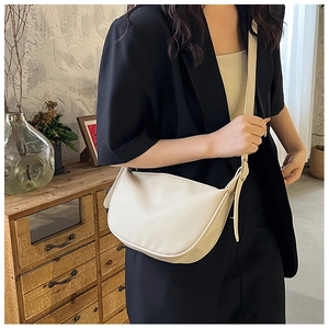 Detail of cream white half-moon crossbody bag with lychee texture and adjustable strap