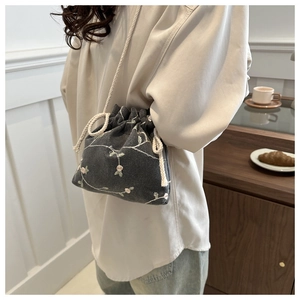 Detail of grey crossbody bucket bag with delicate pink floral embroidery and cotton rope