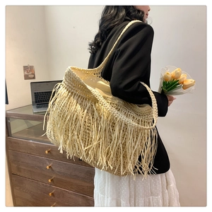 Dettaglio della borsa a spalla in paglia stile boho con frange indossata da una modella