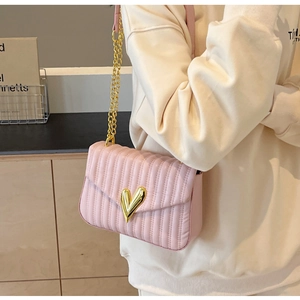Detail of pink quilted PU leather shoulder bag with gold heart lock and chain strap