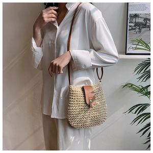 Close-up of woven straw texture with brown leather flap and metal buckle detail