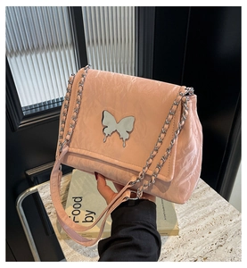 Détail d'un sac en cuir plissé rose clair avec une boucle papillon en métal argenté