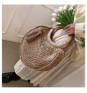 Detail of round straw handbag featuring spiral weave texture and decorative tassel