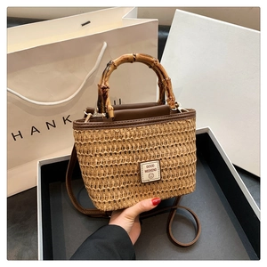 Chic woven handbag with bamboo handles and leather strap presented in a white gift box