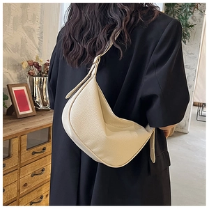 Close-up of beige moon-shaped PU leather handbag with natural texture and wide strap