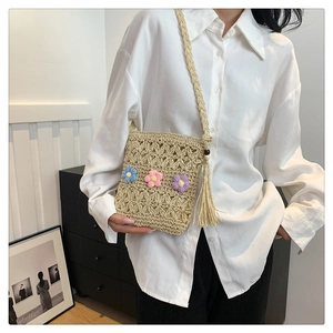 Detailed close-up of handmade straw woven crossbody bag with colorful crochet floral decor